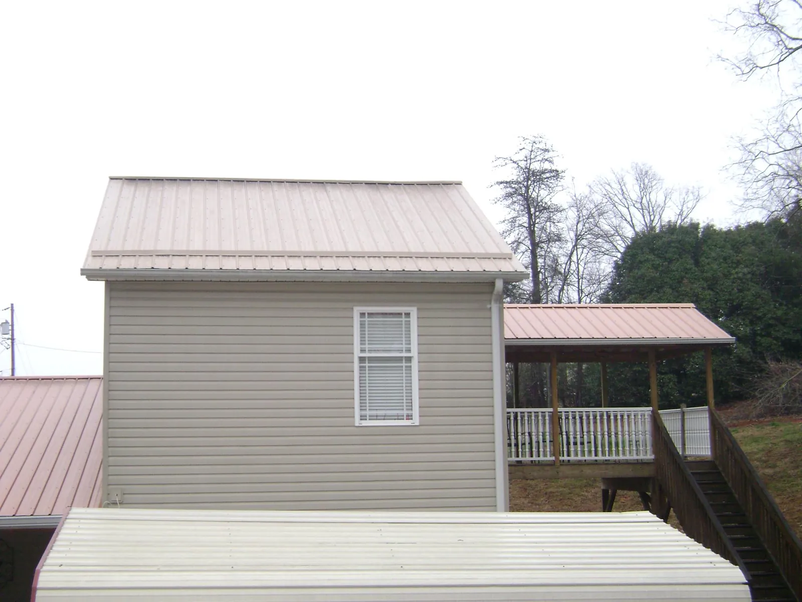 Tan metal roofs on a two story addition and attached porch, from a Roof Replacement job in Stockton